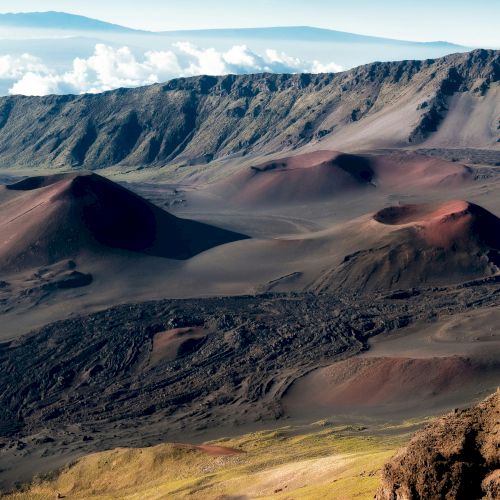 The image showcases a breathtaking volcanic landscape with rolling hills, crater peaks, and rugged terrains under a clear sky.