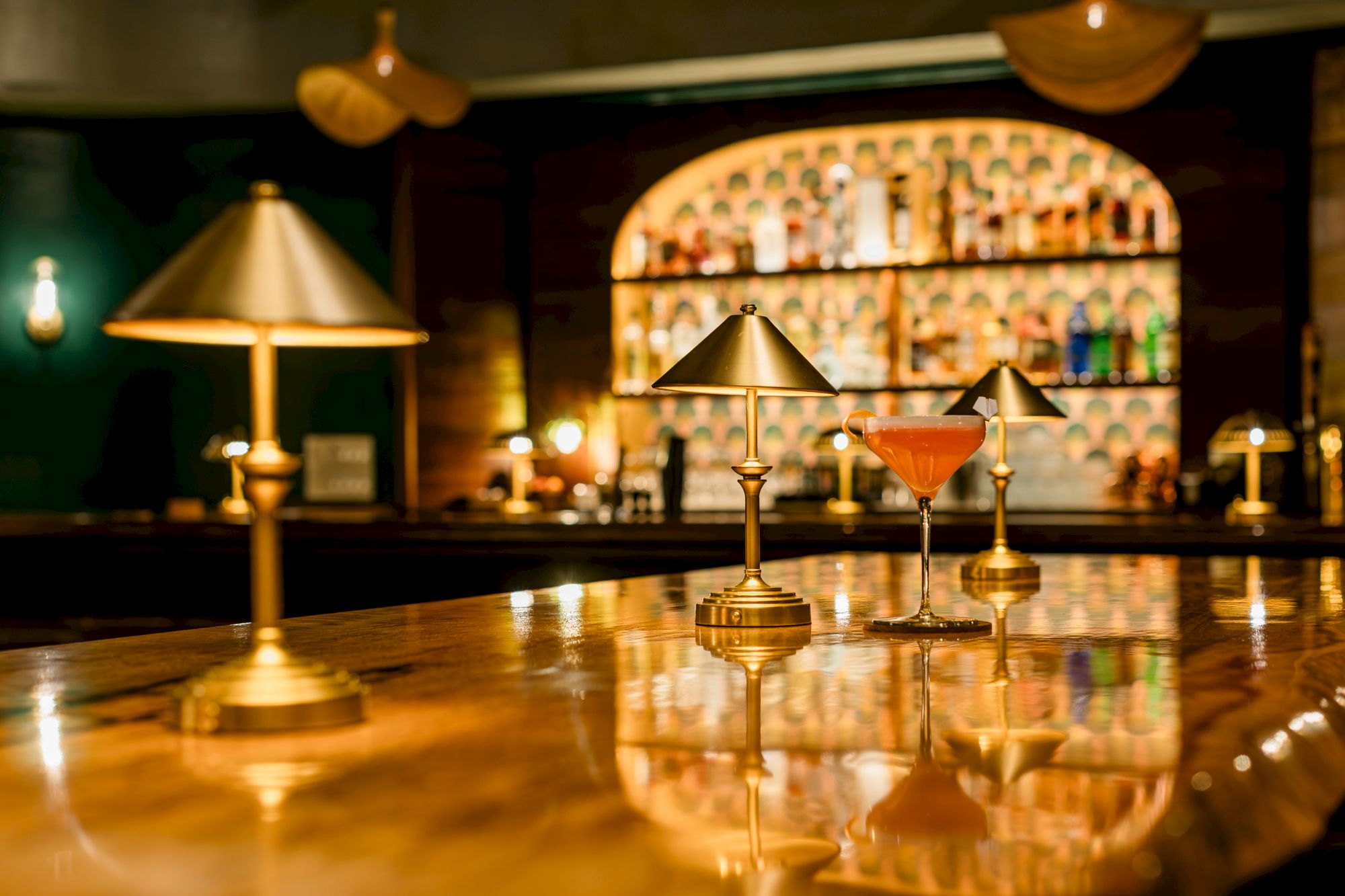 A cozy bar scene with warm lights, a martini glass of amber drink, and a golden hookah on a glossy counter.