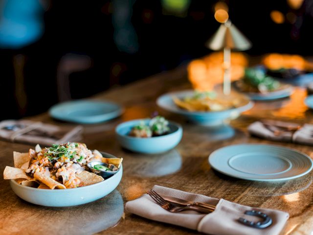 A well-set restaurant table with bowls of food, plates, and a raised condiment stand for serving at dinner time.